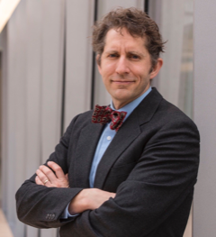 James Evans poses wearing a suit and a bow tie