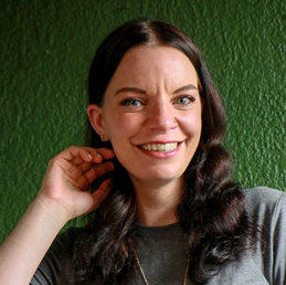 journalist-in-residence Elna Schütz poses in front of green wall