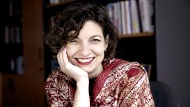 Image of seated woman smiling in front of bookcase