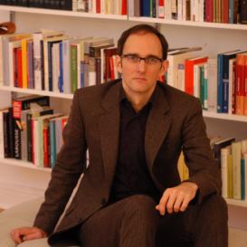 Andreas Mayer posing in front of a book shelf